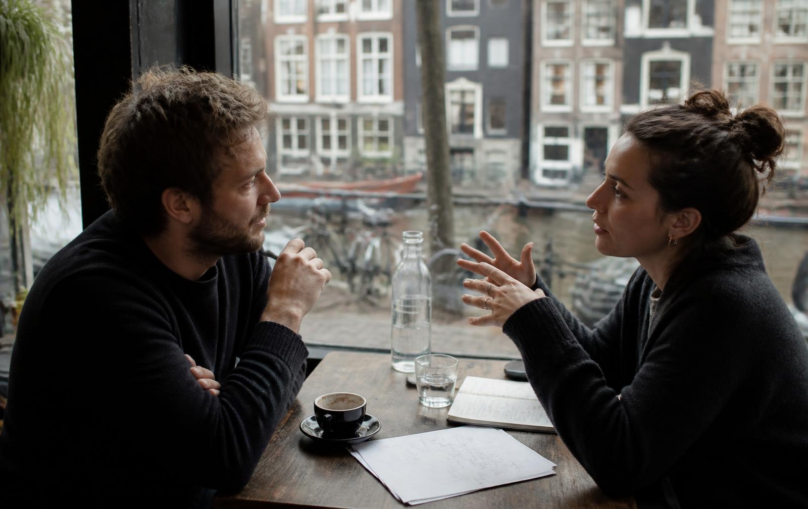 Two people discussing notes across a small café table