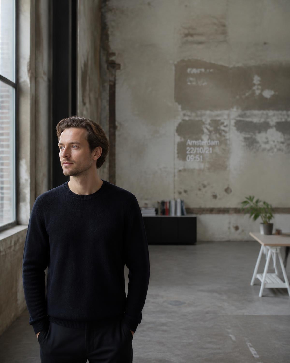 Environmental portrait of a founder in a raw industrial workspace, looking away from camera